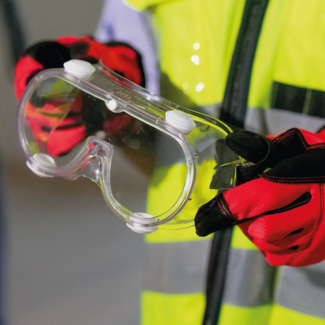 Person in high visibility jacket holding safety goggles